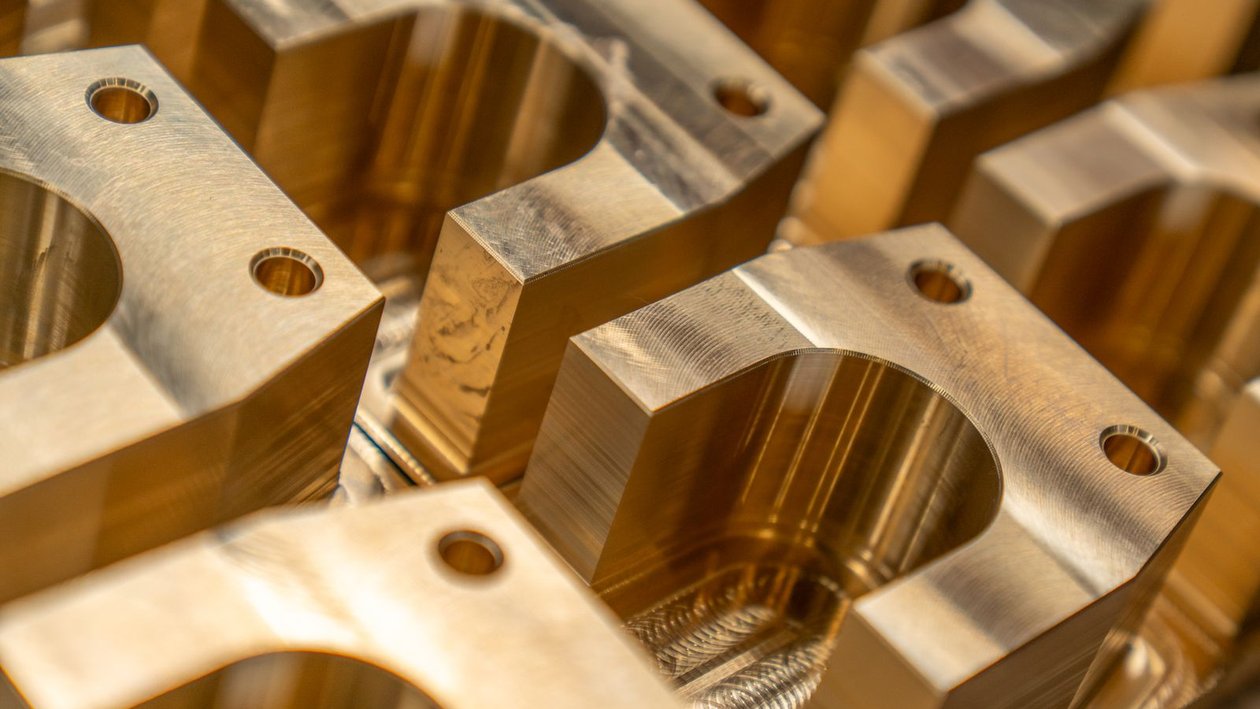 Close up of precision machined brass parts with drilled holes, the kind of work Oklahoma defense suppliers produce.